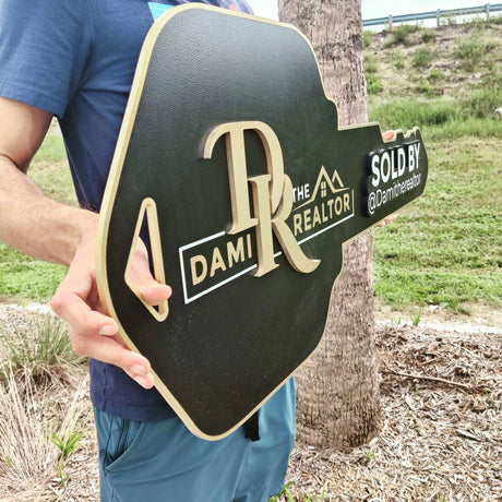 Black Key Shaped Sign with Gold text Logo "Sold by"