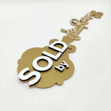 Gold Key-Shaped Sign "Sold By" White Text